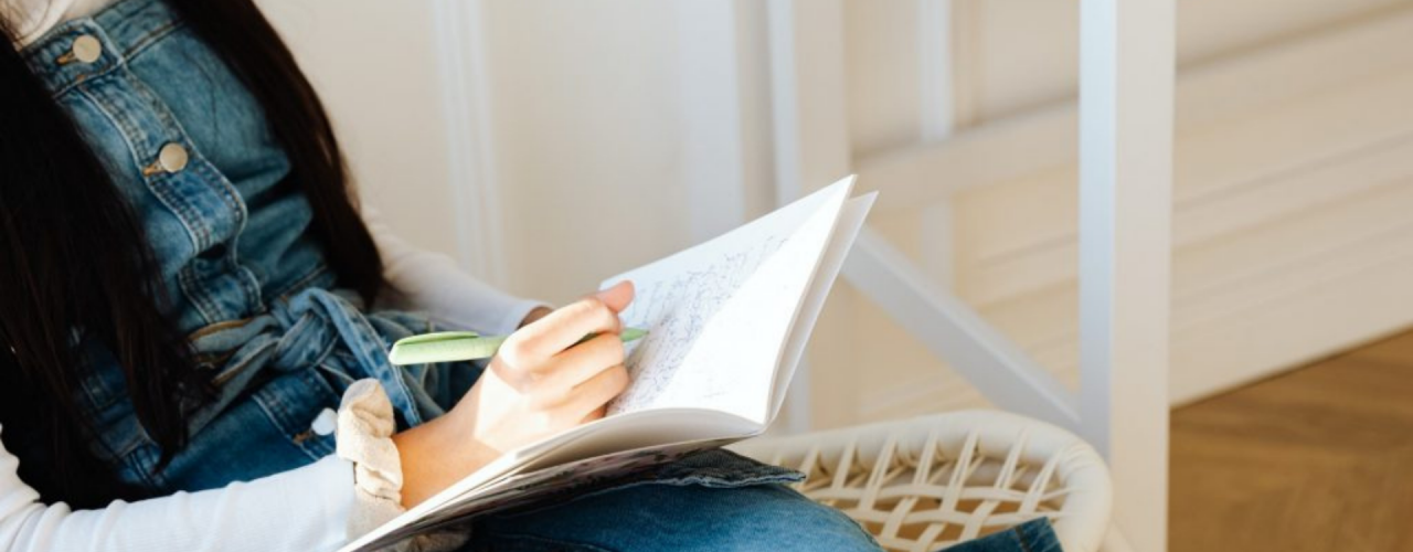 Person sitting in chair writing in a notepad